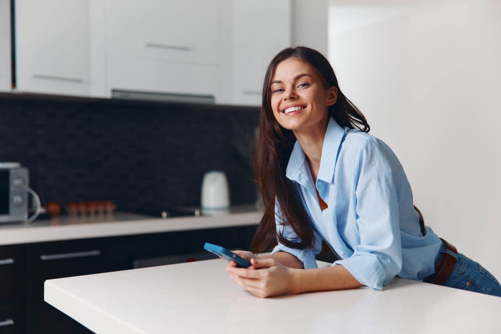 Smiling woman at home checking her phone