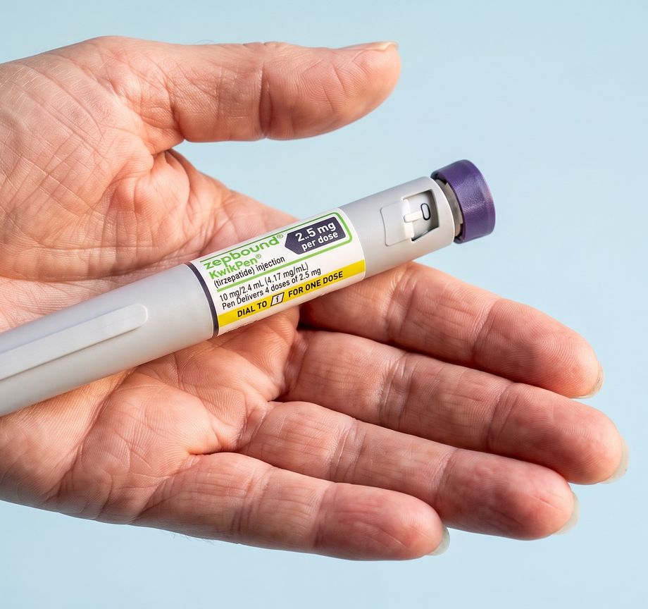 An open hand holding a grey pen with a purple cap