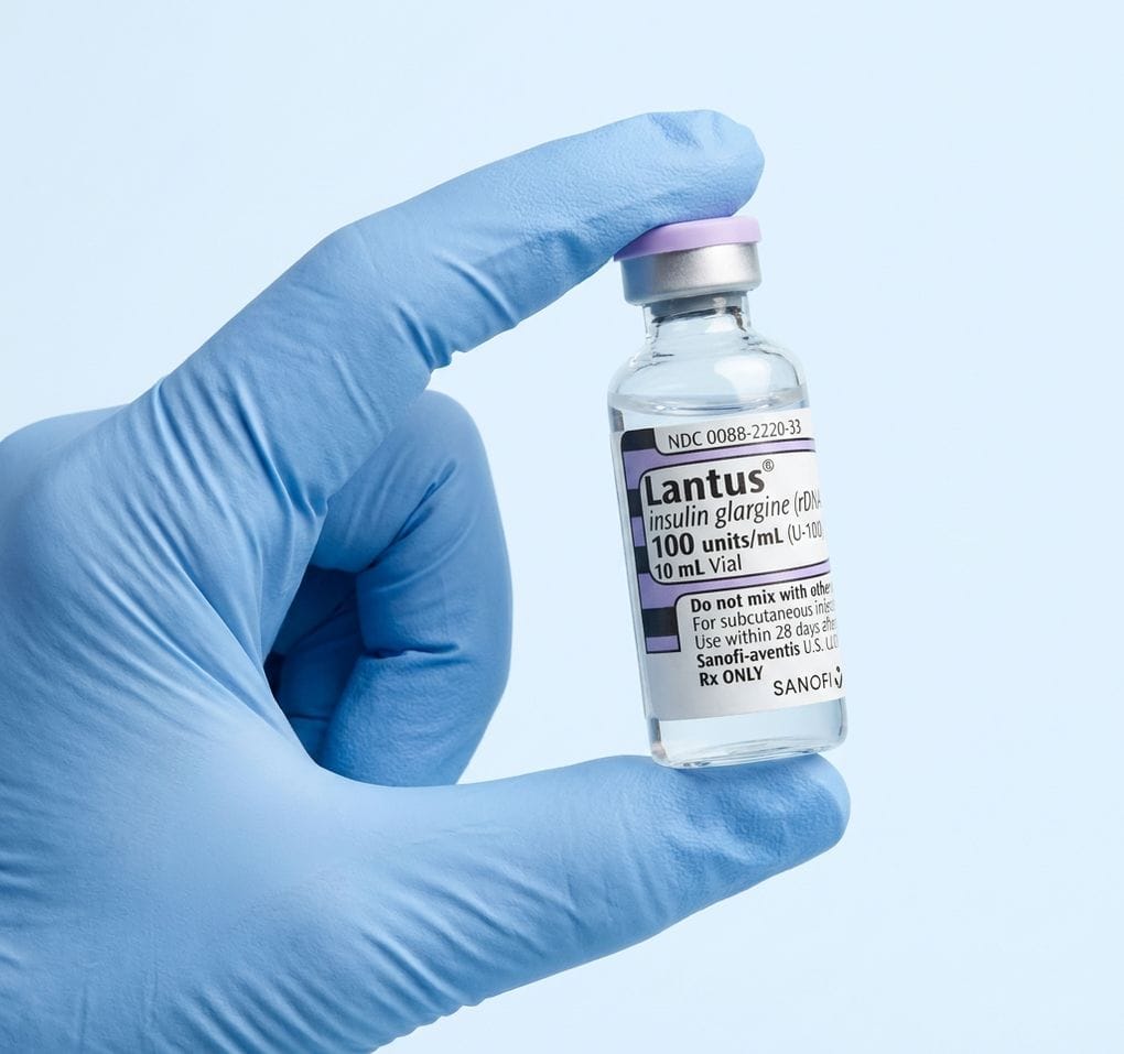 Blue-gloved hand holding a Lantus vial